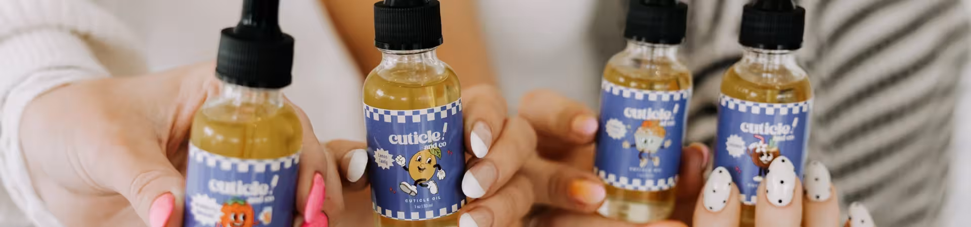Cuticle Co. cuticle oil bottles in manicured hands